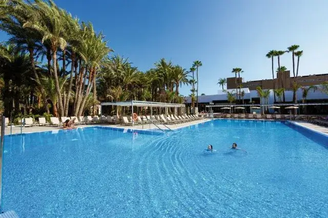 Luxurious Riu Palace Oasis Hotel with private beach access, surrounded by lush gardens and stunning views of Playa de Maspalomas.